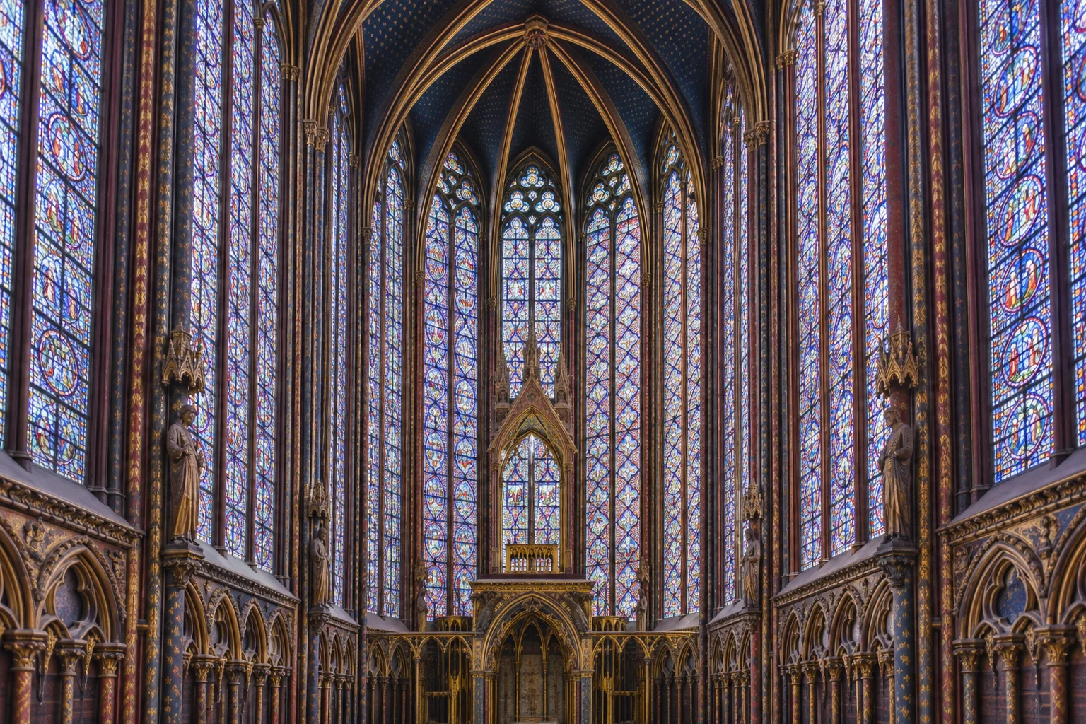 Les hautes verrières colorées de la chapelle haute de la Sainte-Chapelle encadrées par de fins piliers de pierre.