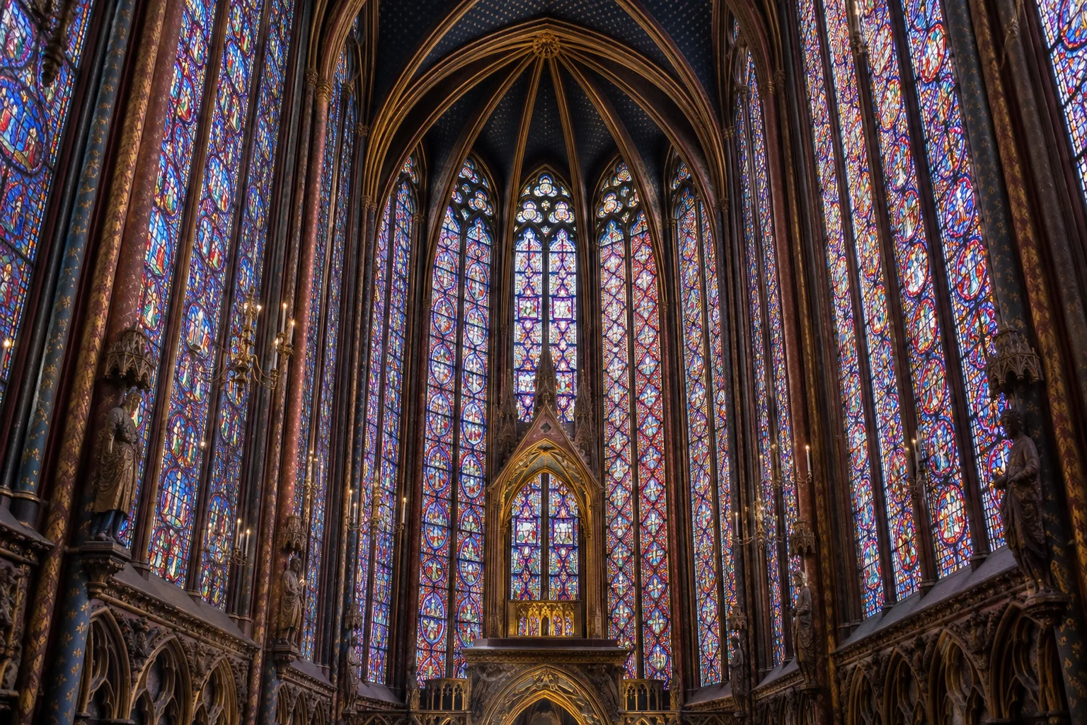 Les hautes verrières colorées de la Sainte-Chapelle s’élèvent au-dessus des fines structures de pierre.