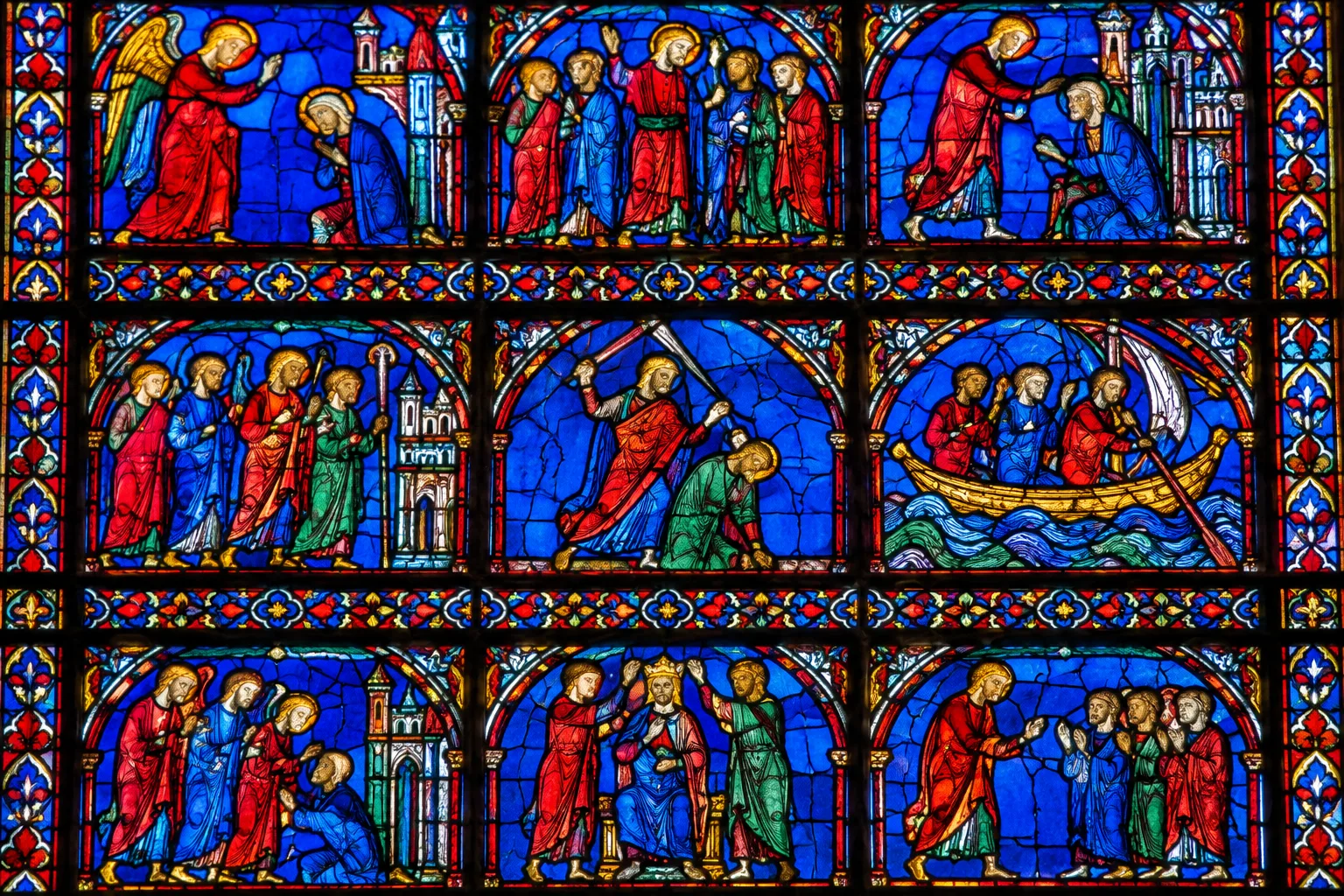 Détail de panneaux de vitrail superposés, où se distinguent des figures et des gestes.