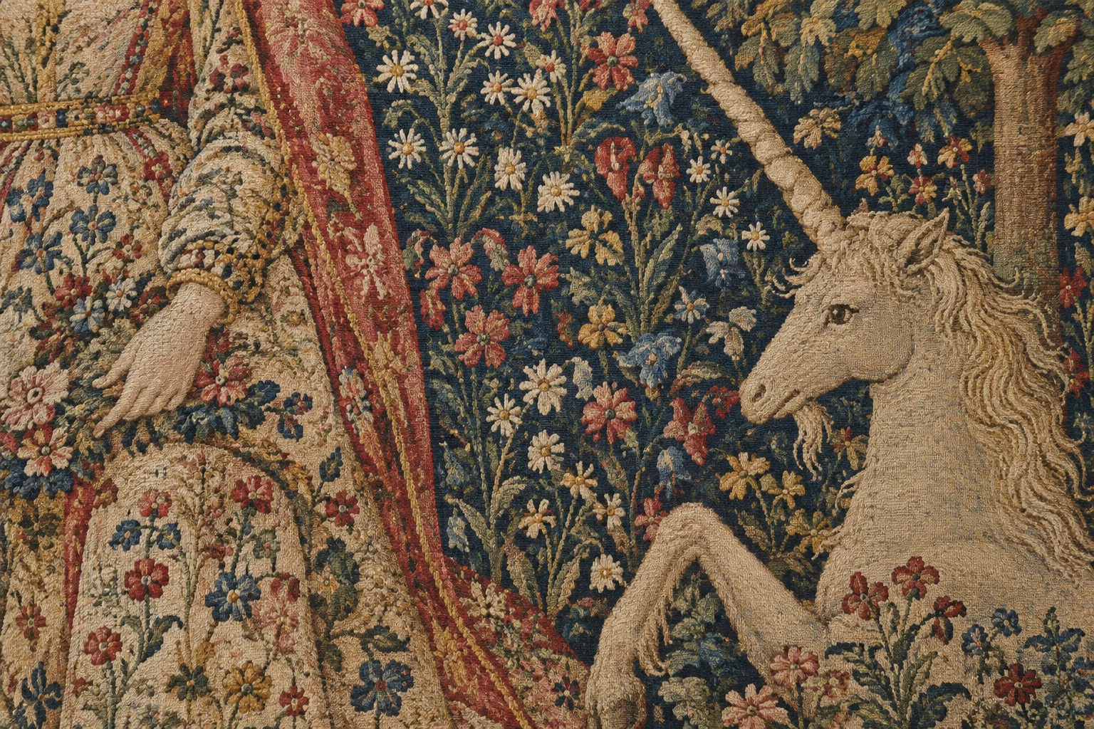 Détail d’une tapisserie millefleurs : fleurs tissées et fragment d’un vêtement près d’une licorne.